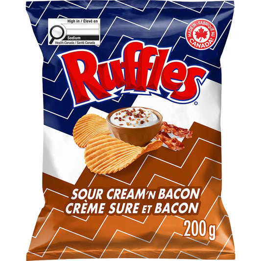 Ruffles Sour Cream 'n Bacon flavored chips packaging with a bowl of dip and bacon bits on a zigzag patterned background.
