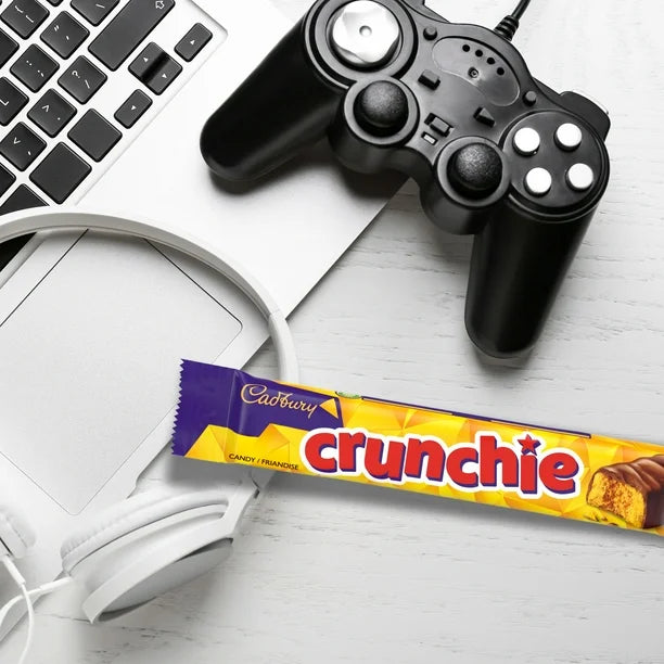 Cadbury Crunchie chocolate bar with a gaming controller and laptop on a white surface