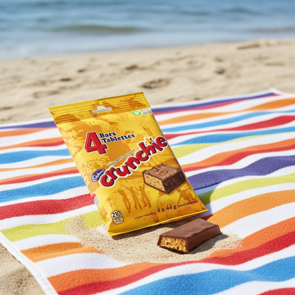 Pack of Crunchie bars on a colorful beach towel with ocean in the background